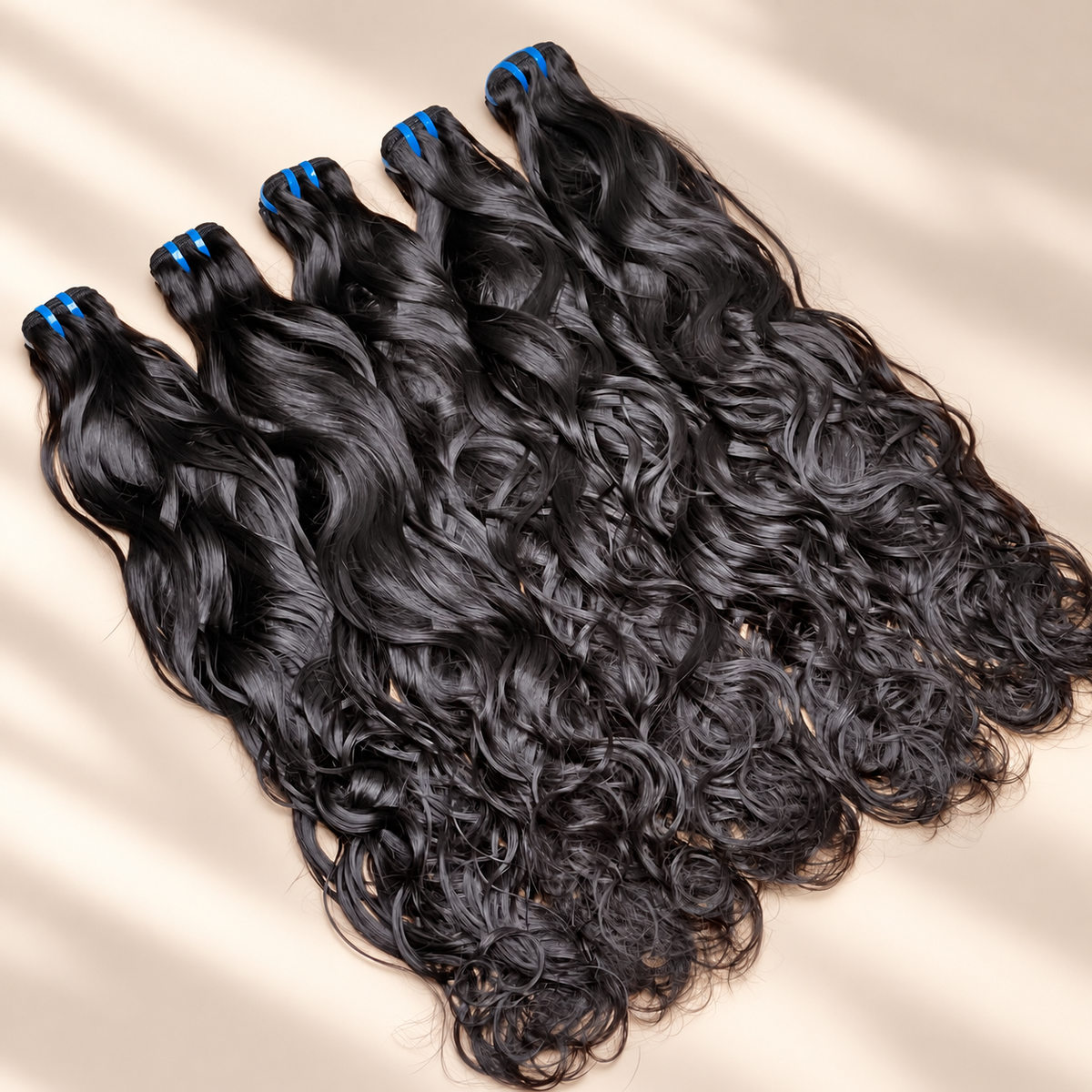 The Siren raw natural wavy bundles in a flat lay against a warm cream studio background