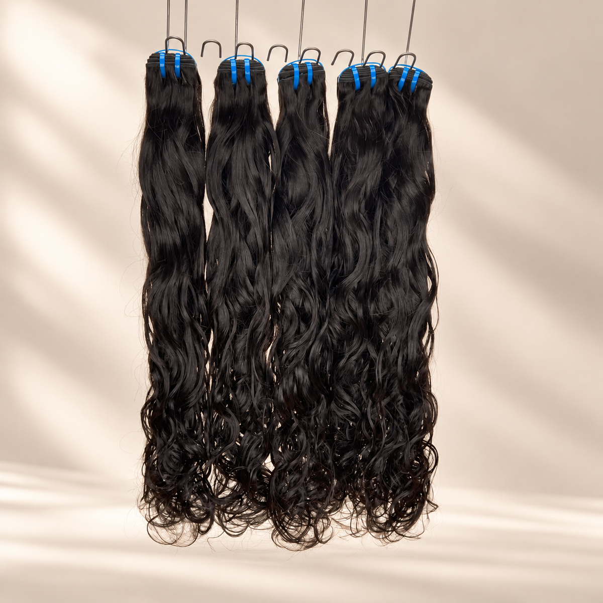 The Siren raw natural wavy bundles hanging against a warm cream studio background