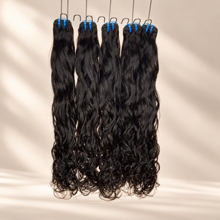 The Siren raw natural wavy bundles hanging against a warm cream studio background