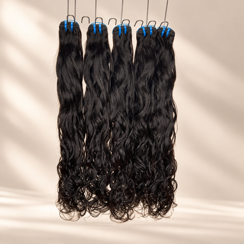 The Siren raw natural wavy bundles hanging against a warm cream studio background